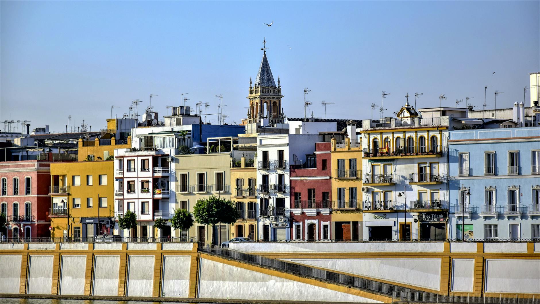 Vibrant and colorful facades of buildings in Calle Betis, Seville, Spain.