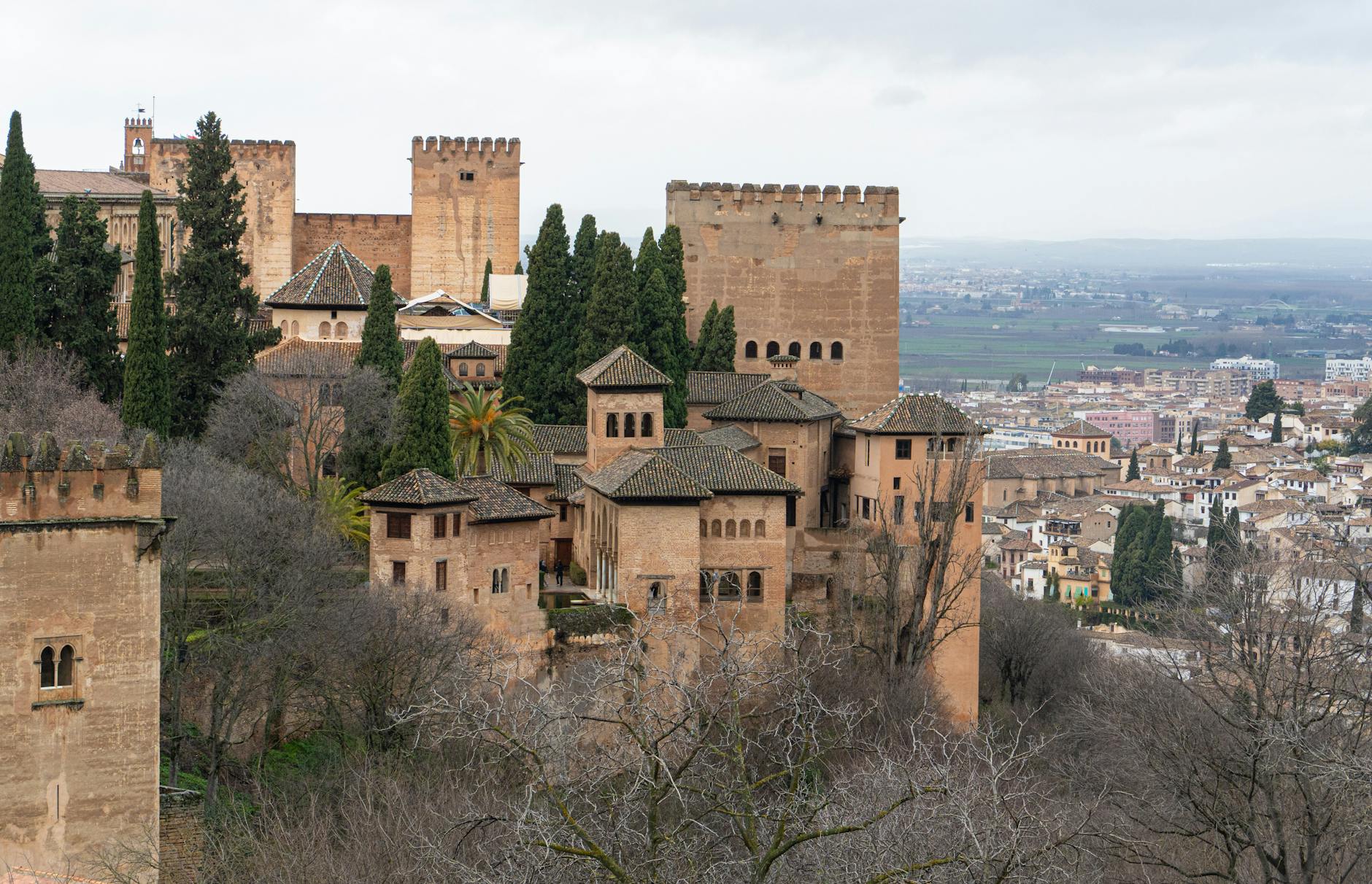 Scenic view of Alhambra fortress surrounded by trees and cityscape in Granada, Spain.