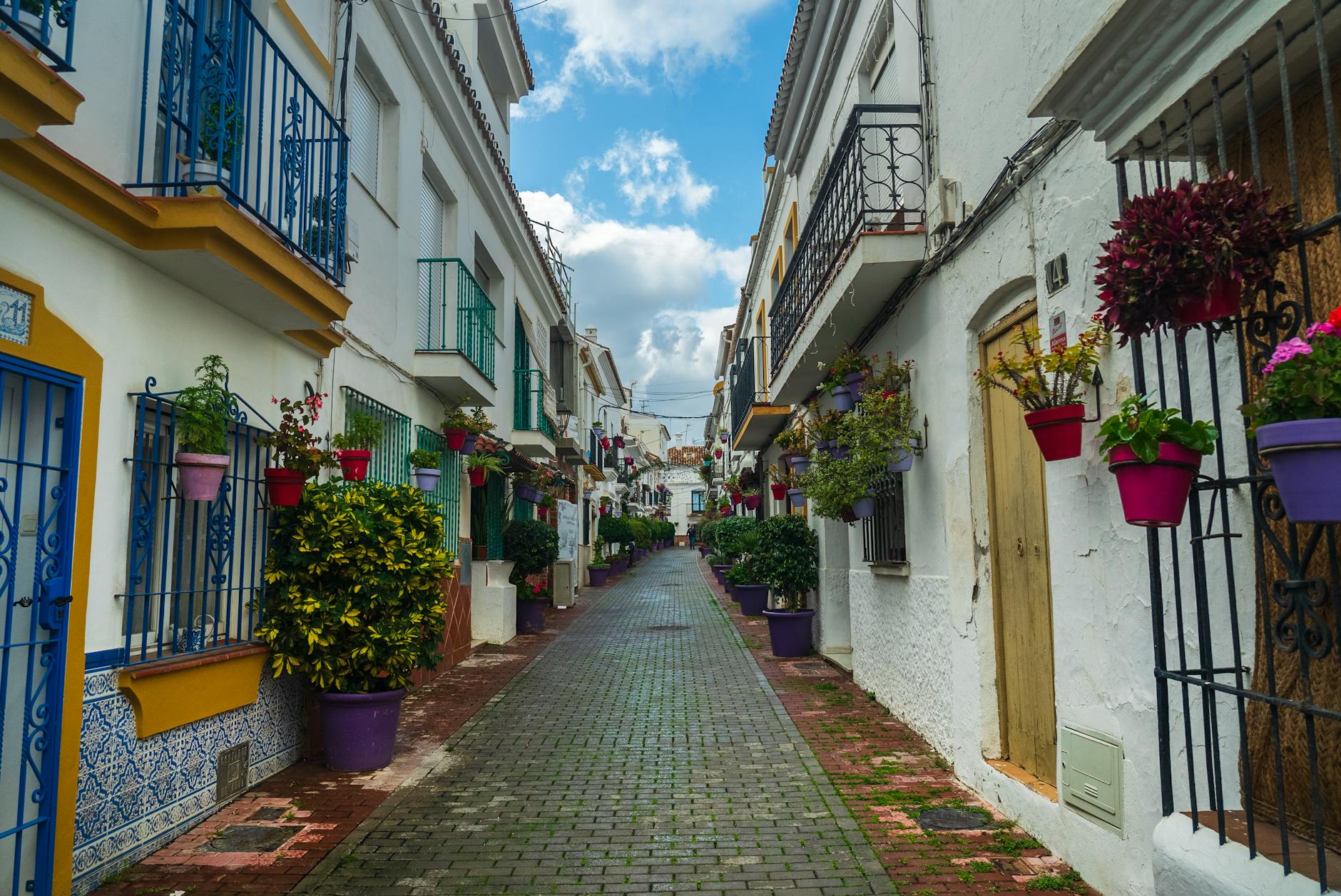 Picturesque alley in Marbella, Spain featuring vibrant flowers and traditional architecture.