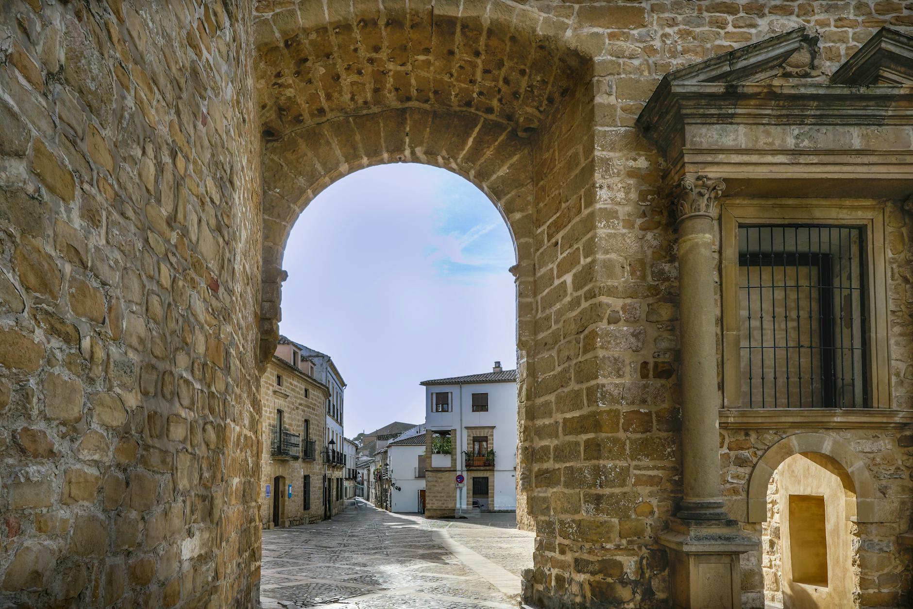 Stone archway and historic street in Baeza, Andalucía, showcasing classic architectural charm.