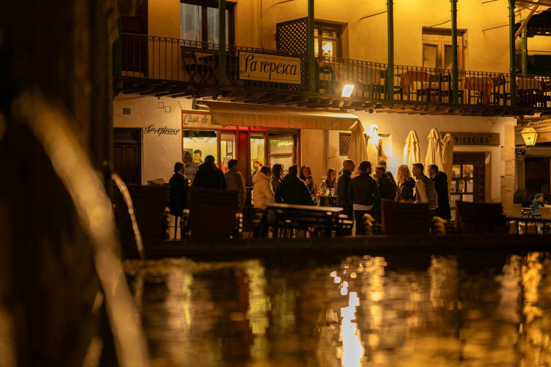 A lively evening scene at a restaurant in Chinchón, Spain featuring a group of people enjoying a warm night out.