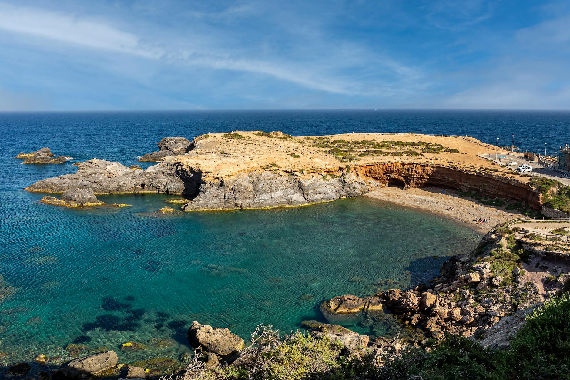 Scenic view of Playa Cabo de Palos coastline with clear Mediterranean waters and rocky formations.