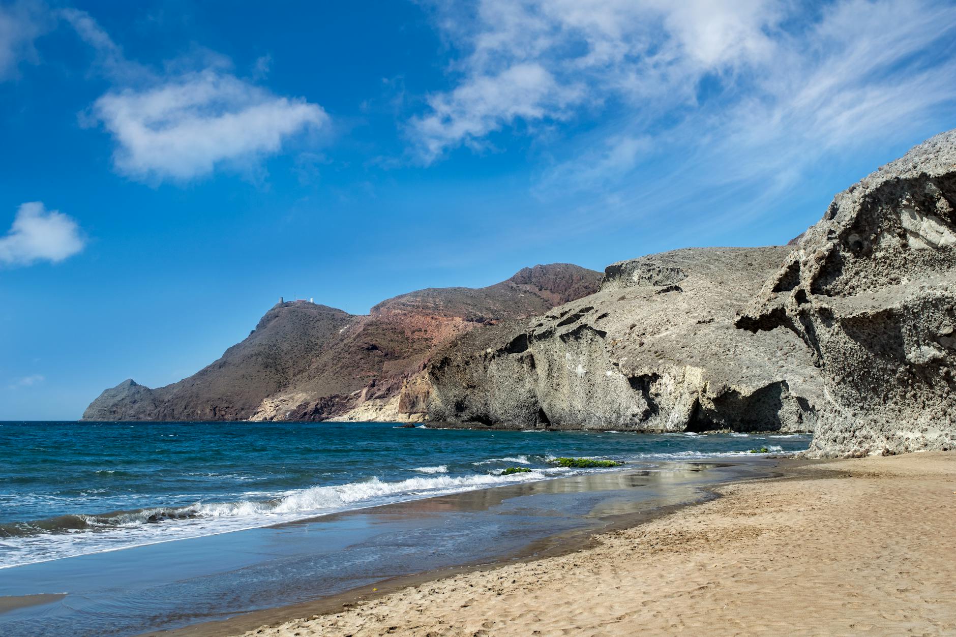 Scenic view of the rugged cliffs and pristine beach in Cabo de Gata, Spain under a clear blue sky.