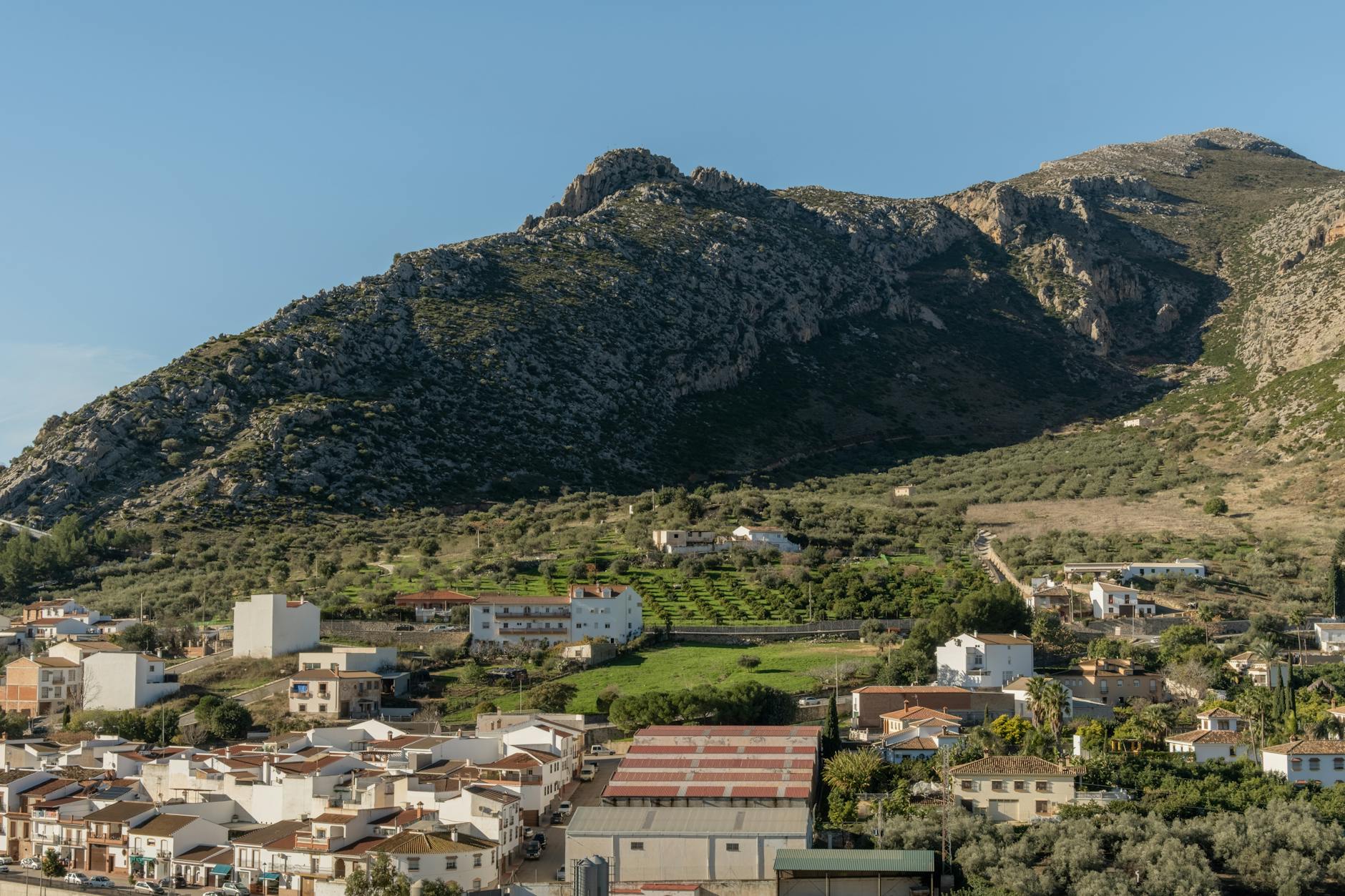 Charming Spanish village with stunning mountain backdrop under clear blue sky.