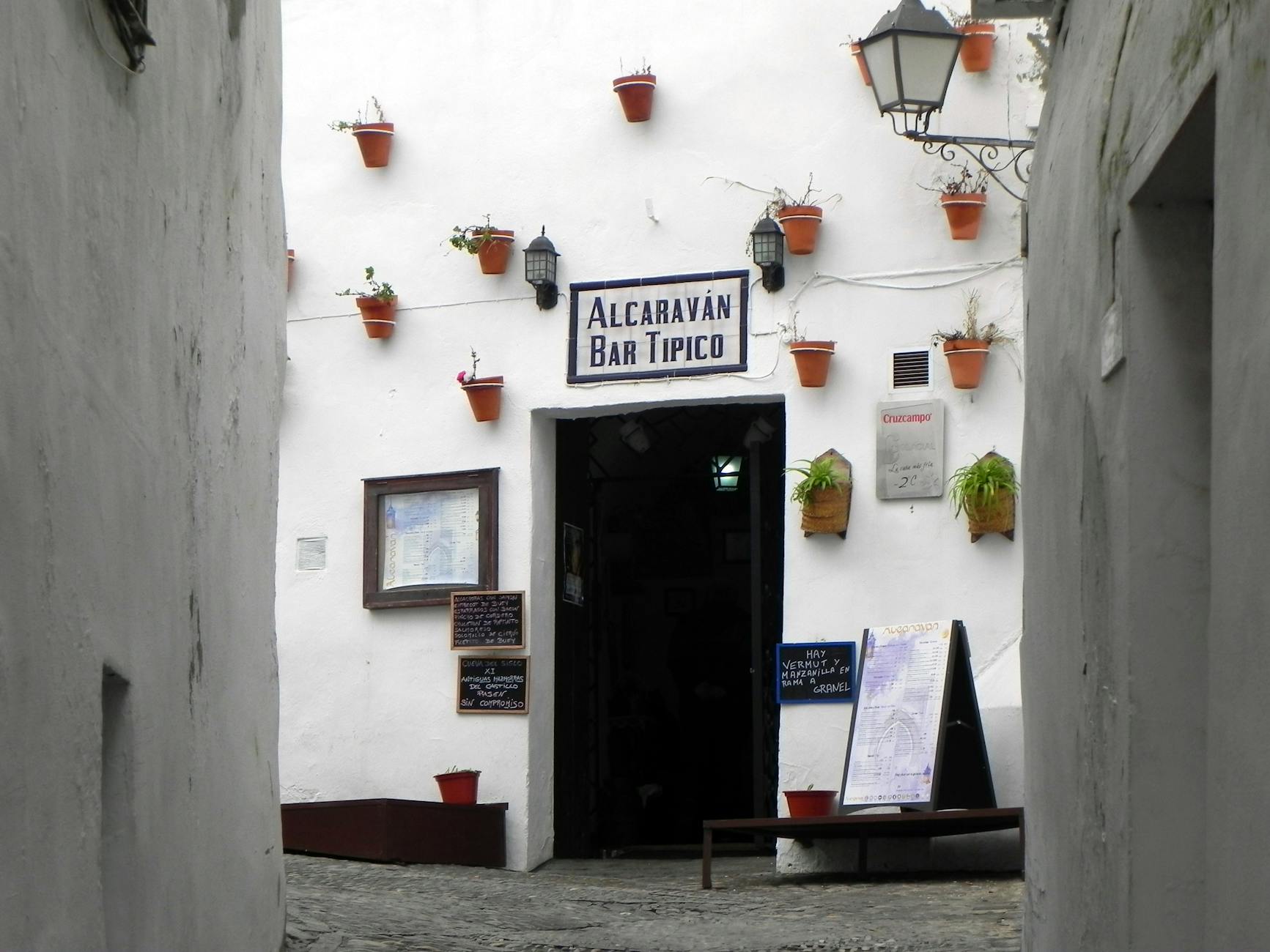 Charming whitewashed alley leading to Alcavarán Bar Típico in Arcos de la Frontera, Spain.