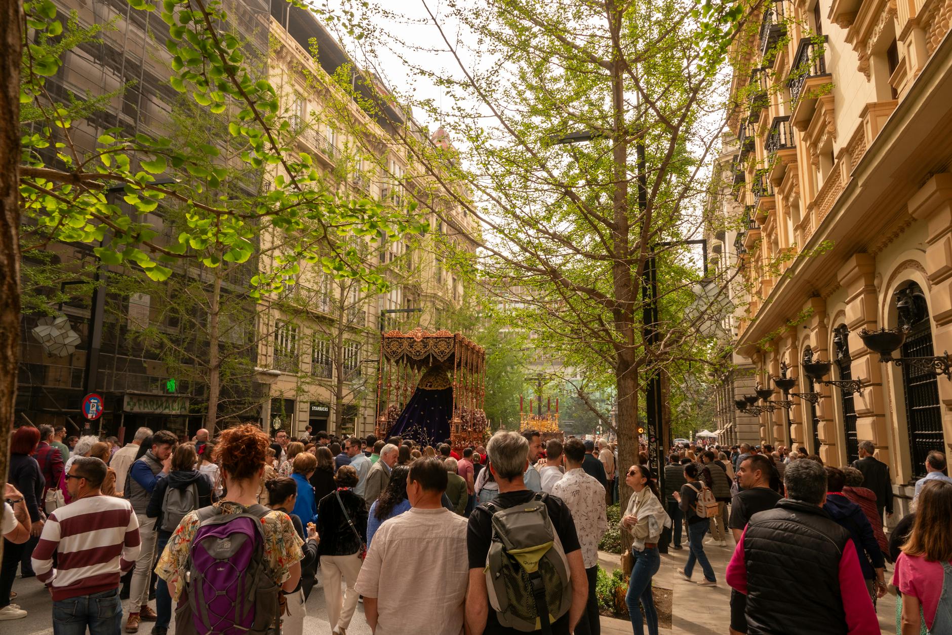 Lively street festival in Granada with a diverse crowd enjoying festivities among historic architecture.