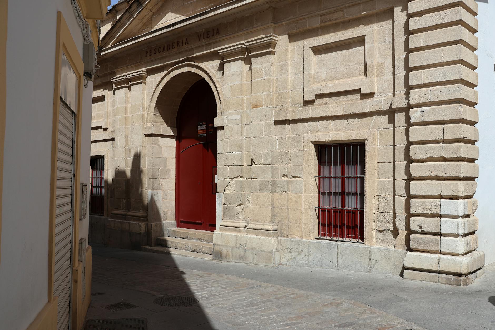 The Pescadería Vieja in Jerez de la Frontera showcases classic architecture with a bold red door and stone facade.