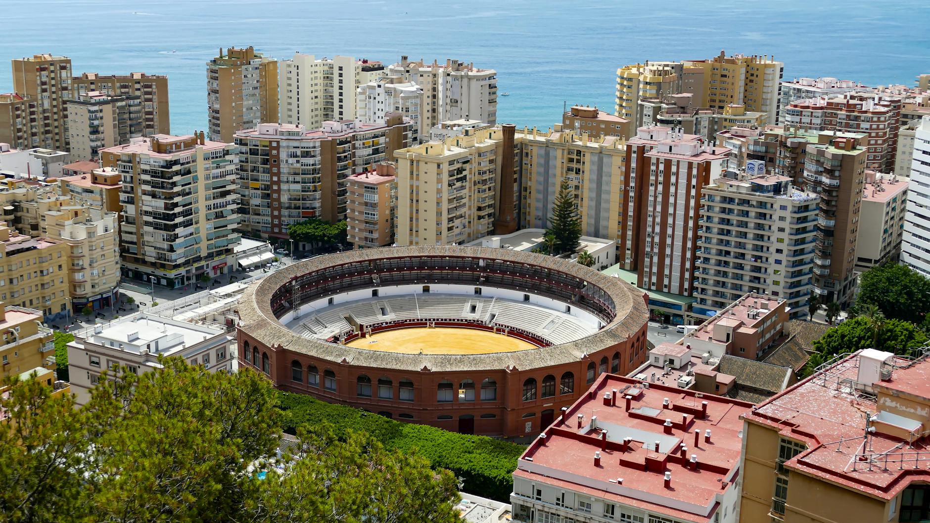 Aerial view of La Malagueta bullring surrounded by Málaga's urban landscape and coastline.