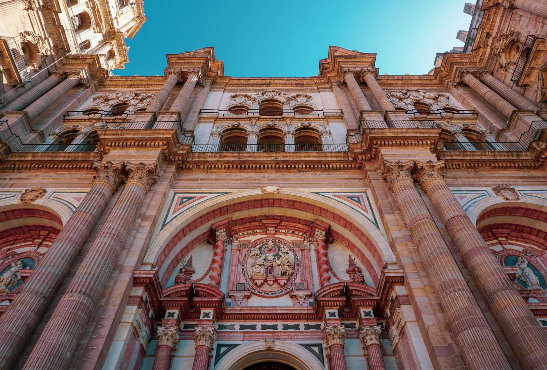 Low angle view of the ornate facade of Málaga Cathedral, showcasing historic architecture and art.