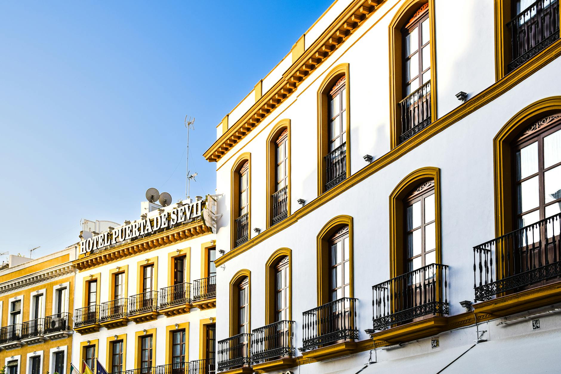 Elegant architectural facade of Hotel Puerta de Sevilla bathed in sunlight, capturing its iconic charm.
