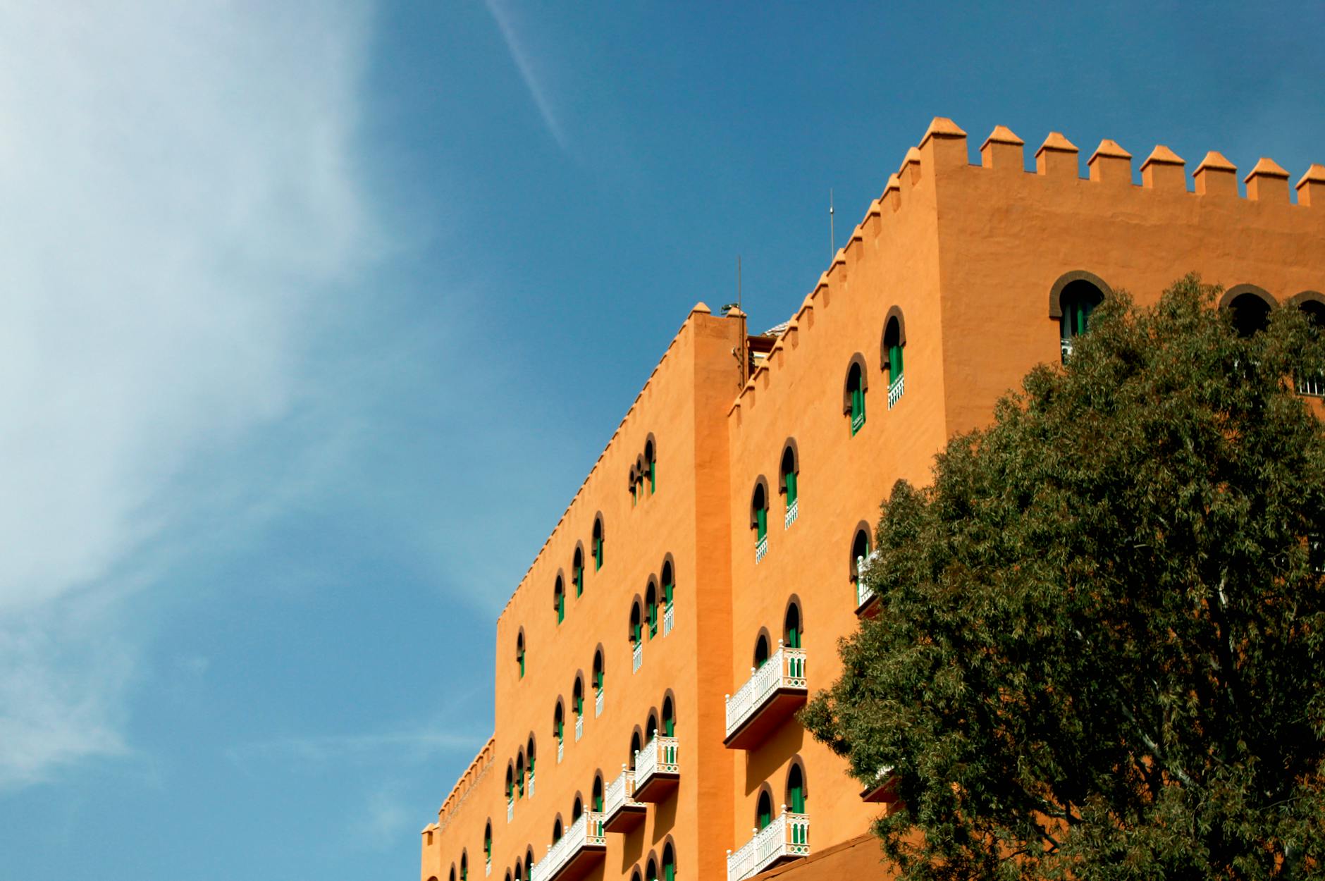 A striking architectural shot of the Alhambra Palace in Granada against a clear blue sky.