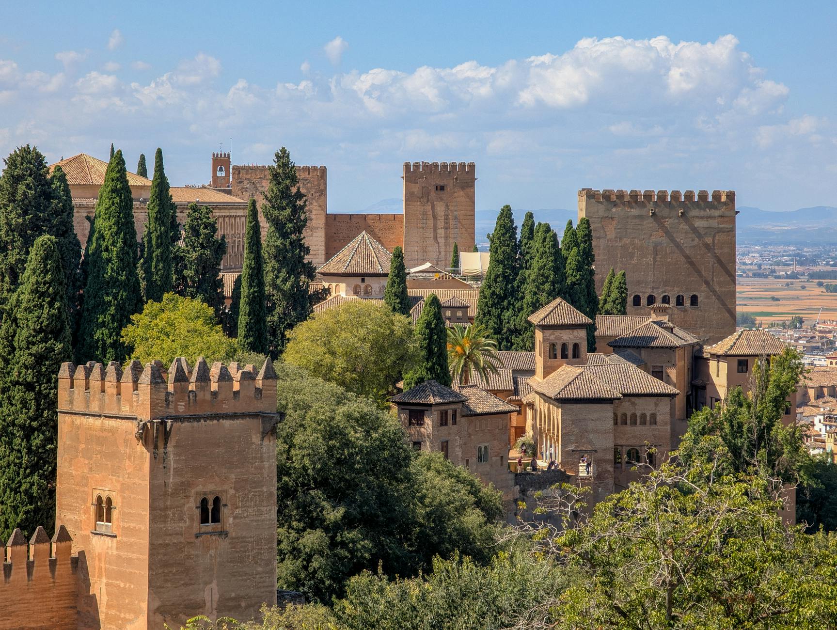 A majestic view of Alhambra in Granada, showcasing its medieval Islamic architecture and lush gardens.
