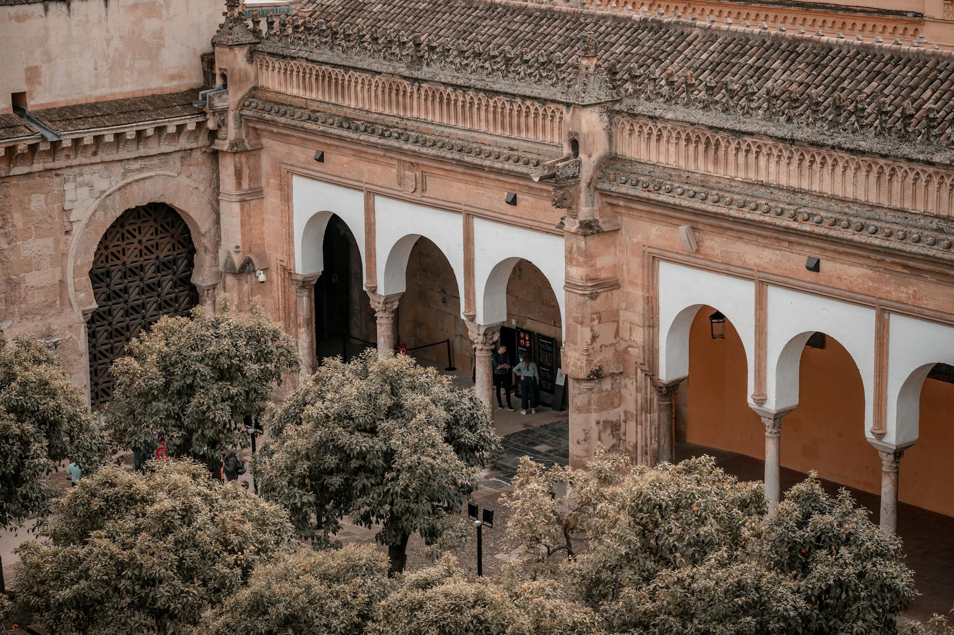 Aerial view of the historic Mosque-Cathedral of Córdoba with its iconic arches and surrounding trees.