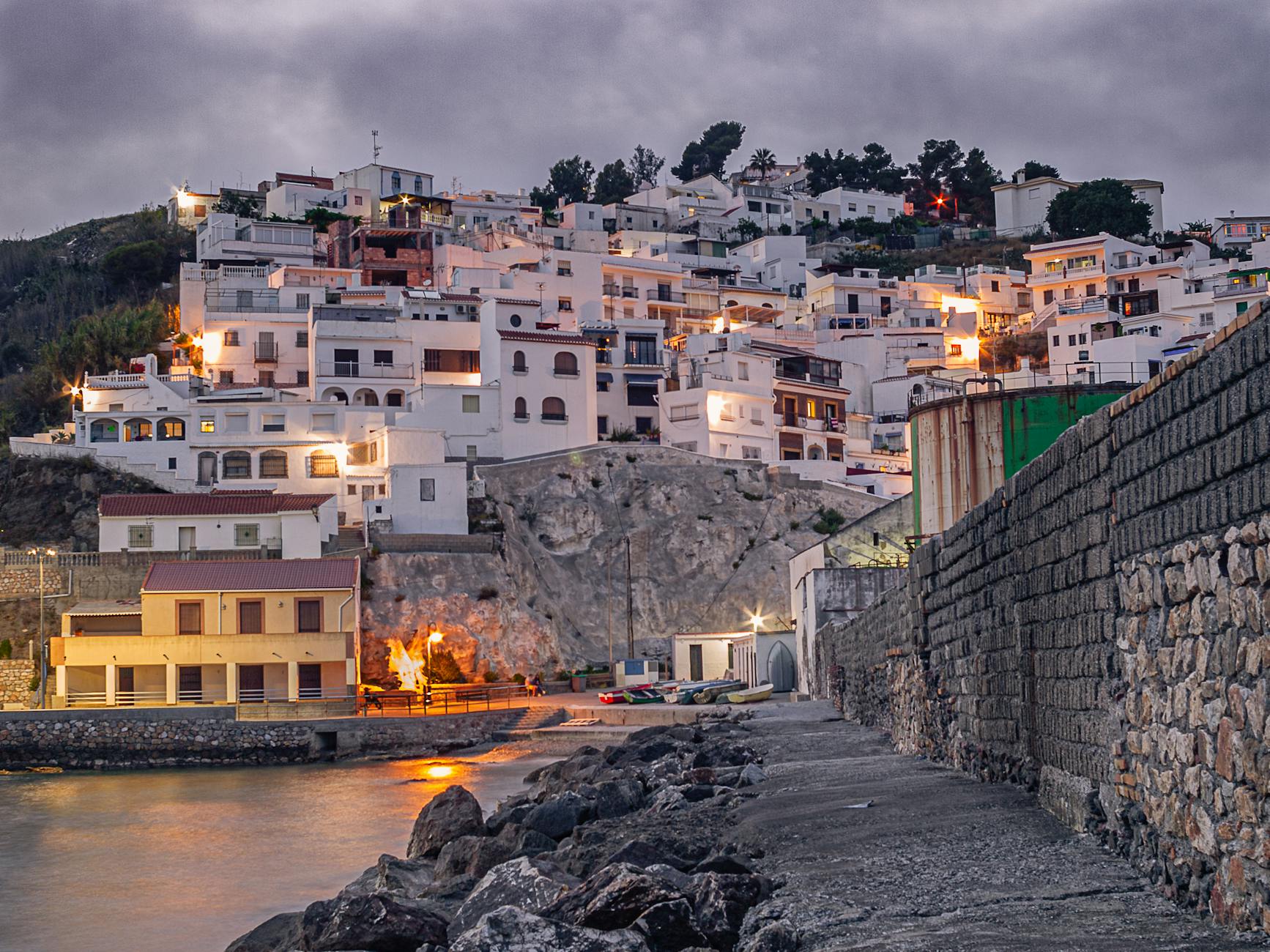 Scenic view of Salobreña, Spain with illuminated white-walled houses on a hill at dusk.