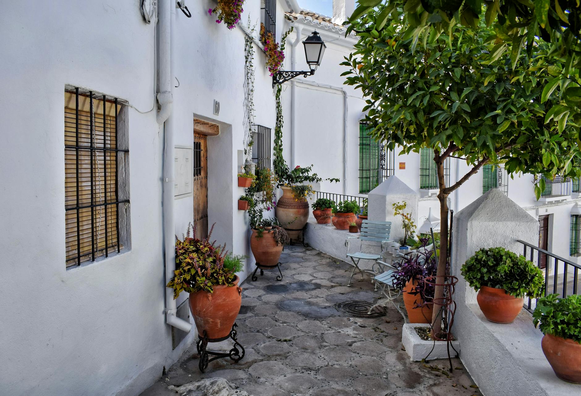 A serene patio in Zuheros, Spain with clay pots and greenery, evoking Mediterranean charm.